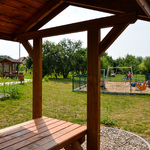 Widok z jednej z altanek na ogrodzony plac zabaw oraz 2 pozostałe altanki