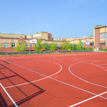 Zdjęcie przedstawia boisko o nawierzchni poliuretanowej do gry w piłkę nożną, piłkę ręczną, koszykówkę i siatkówkę