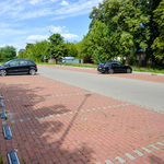 Na parkingu z kostki brukowej stoją dwa samochody.