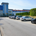 Asfaltowa ulica, wzdłuż której na parkingu po prawej stronie ustawione są samochody.