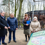 Prezydent z grupą ludzi stoi w Zoo przy tablicach informacyjnych.