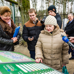 Kobieta wraz z innymi osobami stoją przy terminalach informacyjnych w zoo.
