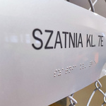 tabliczka informacyjna zawierająca tekst w języku Braila. Na tabliczce napis: Szatnia klasy 7 e.