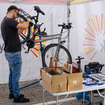 Rower wisi na stojaku. Stojący tyłem mężczyzna naprawia go.