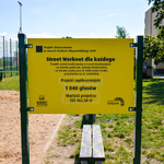 W centrum żółta tablica informująca o realizacji projektu. W tle drzewa.