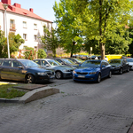 Parking przed budynkiem. Samochody. W tle drzewo i blok.