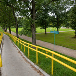 Widok na park, na pierwszym planie zjazd dla rowerów. W oddali ścieżki parkowe i drzewa.