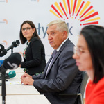 Trzy osoby siedzące za stołem konferencyjnym