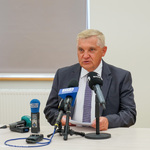 Prezydent Miasta siedzący za stołem konferencyjnym i mówiący do mikrofonu
