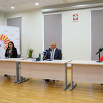 Trzy osoby siedzące za stołem konferencyjnym
