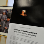 Wydruk karty informacyjnej o wystawie. w tle jedna z fotografii umieszczona na sztaludze.