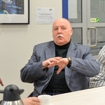 Kilka osób siedzących przy stole rozmawia w parach.