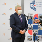 Jasne pomieszczenie. Prezydent Białegostoku mówi do mikrofonu na statywie i mikrofonów trzymanych  w dłoniach osób znajdujących się poza kadrem.