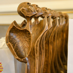 Osiem rzeźbionych w drewnie figurek ustawionych w rzędzie. 
