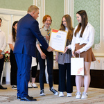 Wnętrze auli. Prezydent Białegostoku wręcza na scenie dyplom kilku wolontariuszkom. 