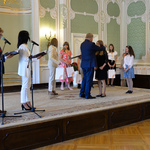 Wnętrze auli. Prezydent Białegostoku wręcza na scenie upominki wolontariuszkom. 