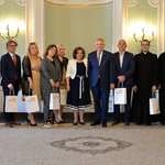 Wnętrze auli. Prezydent Białegostoku pozuje do zdjęcia z kapitułą konkursu. 