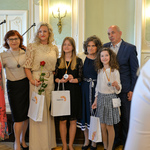 Wnętrze auli. Młode wolontariuszki pozują do zdjęcia ze swoimi opiekunami. 