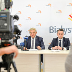 Prezydent miasta i jego zastępca prezentują wyniki głosowania siedząc przy stole konferencyjnym.