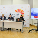 Jasne pomieszczenie. Prezydent miasta wraz z zastępcą, dyrektorką Centrum Aktywności Społecznej i rzeczniczką prasową Urzędu Miejskiego siedzą przy stole konferencyjnym ustawionym na tle logo miasta. 