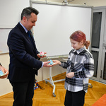 Dziewczynka wręcza zastępcy prezydenta miasta kwiat zrobiony techniką origami. 