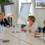 Pani Pełnomocnik Prezydenta Miasta Białegostoku do spraw równego traktowania siedzi z uczestniczkami spotkania przy stole.