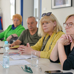 Trzy kobiety i mężczyzna siedzą przy stole, patrzą w jednym kierunku, słuchają wypowiedzi.
