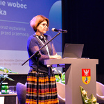 Przedstawicielka organizacji Unicef mówi do zebranych stojąc na scenie.