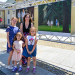 Kobieta z trójką córek pozuje do zdjęcia obok planszy wystawowej.