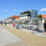 Pogodny dzień, Rynek Kościuszki w Białymstoku. Na pierwszym planie aluminiowy stelaż z planszami fotograficznymi. W tle ratusz i inne budynki miejskie. 