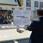 Zastępca Prezydenta Miasta stoi zwrócony w kierunku planszy informacyjnej dotyczącej wystawy.