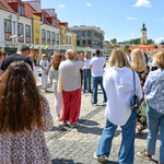 Tłum ludzi zgromadzony w czasie otwarcia wystawy. Wśród nich widać autora zdjęć mówiącego do mikrofonu.