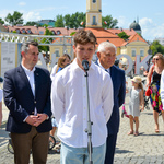 Uczestnik projektu Wspólnie mówi do mikrofonu. Obok stoją inni uczestnicy wernisażu. 