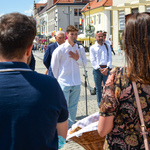 Uczestnik projektu Wspólnie mówi do mikrofonu. Obok stoją inni uczestnicy wernisażu. 