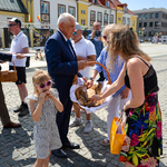Prezydent miasto trzyma w dłoniach duży wiklinowy kosz z kromkami chleba, które rozdaje uczestnikom wydarzenia. Obok jego zastępca rozdaje pamiątkowe broszury. 