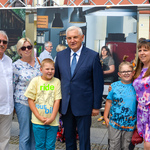 Uczestnicy projektu Wspólnie oraz prezydent miasta pozują do zdjęcia jednej z wystawowych plansz. 