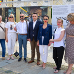 Autor fotografii, zastępca prezydenta, Dyrektorka Centrum Aktywności Społecznej i przedstawiciele delegacji z Łucka pozują do zdjęcia na tle wystawy. 