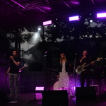 Na scenie gra czteroosobowy zespół: jedna kobieta i trzech mężczyzn. Jest zmrok. Świecą fioletowe światła.