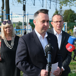 Konferencja prasowa na terenie siłowni pod chmurką. Zastępca prezydenta miasta mówi do mikrofonów dziennikarzy.