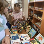 Trzy dziewczynki oglądają wystawę audiobooków.