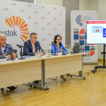 Konferencja prasowa dotycząca projektów zgłoszonych do Budżetu Obywatelskiego. Duże, jasne pomieszczenie. Uczestnicy konferencji siedzą przy długim stole, na którym stoją mikrofony przedstawicieli mediów. Obok stołu telewizor, na którym wyświetlona jest grafika dotycząca projektów.