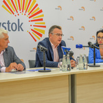 Uczestnicy konferencji siedzący za stołem. Zastępca prezydenta miasta mówi do mikrofonu.
