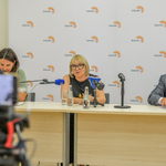 Uczestnicy konferencji siedzący za stołem. Radna Miasta Białystok mówi do mikrofonu.