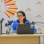 Dyrektorka Centrum Aktywności Społecznej mówi do mikrofonu siedząc za stołem konferencyjnym.