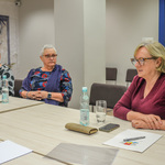 Przewodnicząca rady mówi do uczestniczek spotkania siedzących przy stole. 