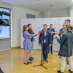 Konferencja prasowa. Przedstawiciel Stowarzyszenia My dla Innych odpowiada na pytania trzymających mikrofony dziennikarzy.