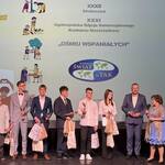 Gala wręczenia nagród. Młodzi wolontariusze i wolontariuszki stoją na scenie, w dłoniach trzymają nagrody.