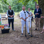Przedstawiciel ogranizacji realizującej projekt mówi do mirofonu. W tle pozostali uczestnicy konferencji prasowej.